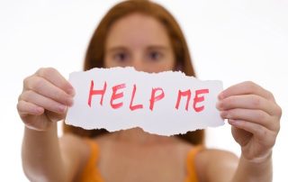 Girl holding up HELP ME sign.