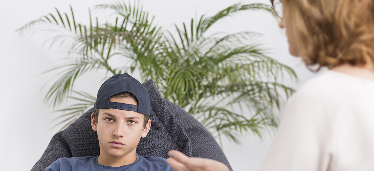 Angry boy sitting with therapist