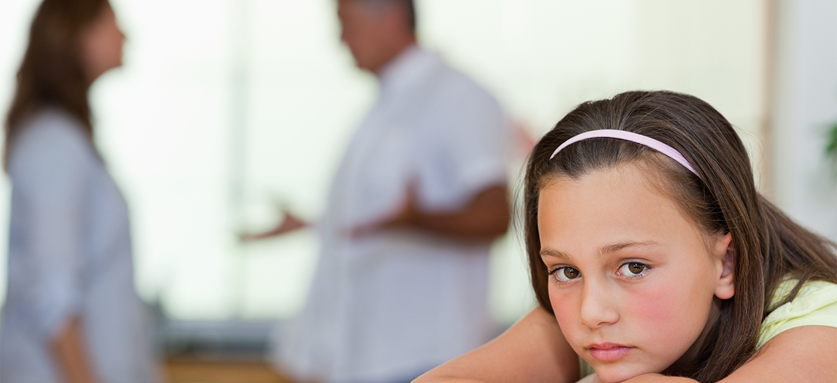 Child with parents in the background arguing