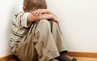 Child sitting in corner with head down