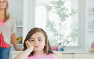 Pouting child with angry parent in background (1)