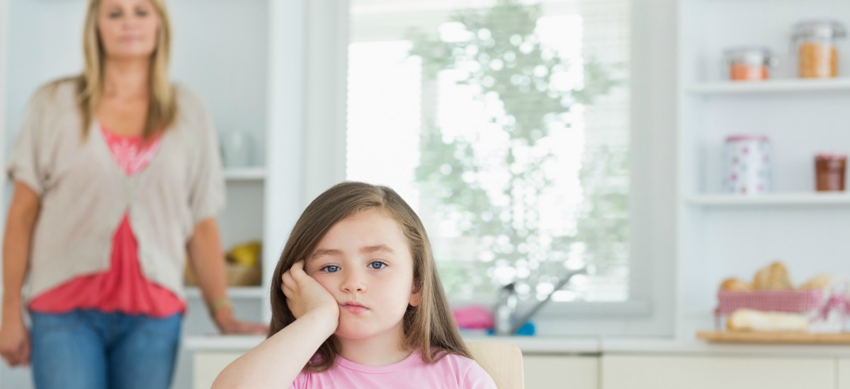 Pouting child with angry parent in background (1)